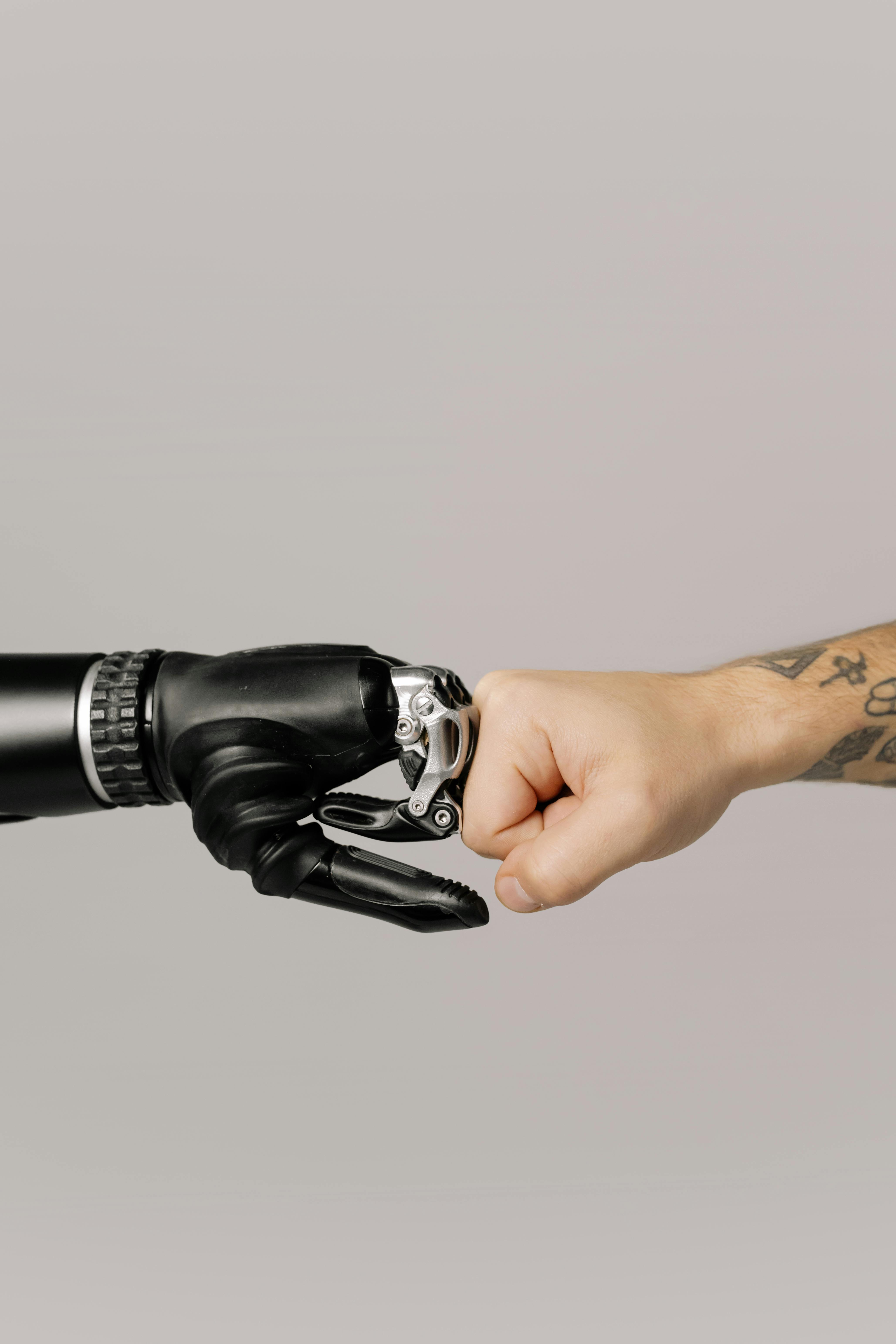 Robot hand and human hand fist bump representing human-AI collaboration